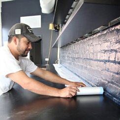 Man applying plastic masking film on the surface of an under-construction kitchen