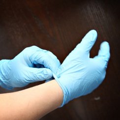 A man's hands while putting on blue nitrile gloves