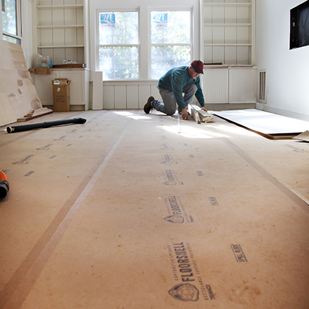 temporary floor protection rolls laid flat on a floor with a man working