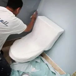painting around a toilet covered with Trimaco's toilet cover