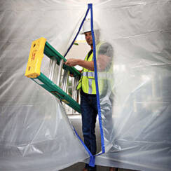 man in a construction hat and safety vest bringing a ladder through sheet plastic with a magnetic zipper opening