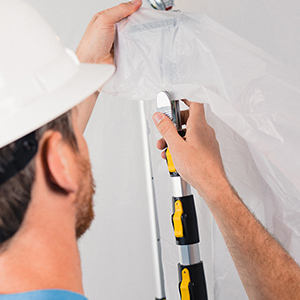 man in hard hat clipping plastic sheeting to the heavy-duty E-Z Up Dust Containment Pole