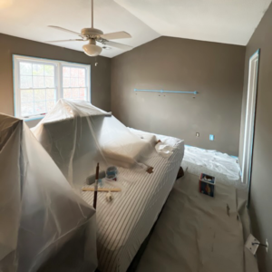 room prepared for painting with furniture moved to the center covered with plastic sheeting